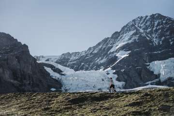 A runner on the mountain course of the Jungfrau Marathon. Scattered snowfields and glaciers on the mountain can be seen in the background.