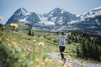 A runner on the mountain course of the Jungfrau Marathon. The Eiger, Mönch, and Jungfrau can be seen in the background.