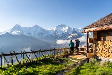 Hikers enjoy the panoramic view of the Eiger, Mönch, and Jungfrau at the Lobhorn Hut.