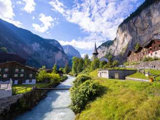 The Lütschine River flows through the village of Lauterbrunnen. The church stands next to the river, nestled between the steep cliffs of the Lauterbrunnen Valley.