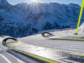Skiers pose on the slope in Mürren-Schilthorn. The trio of the Eiger, Mönch, and Jungfrau can be seen in the distance.