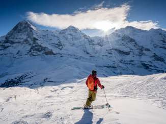 Skiing in the Grindelwald–Wengen ski area. The skier takes a break and enjoys the panoramic view of the Eiger, Mönch, and Jungfrau.