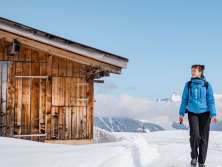 Aus der Vogelperspektive zeigt sich die verschneite Landschaft entlang der BLM-Strecke zwischen Grütschalp und Mürren. Die Bahnlinie führt durch weisse Hänge, vorbei an einzelnen Hütten und Tannen mit Blick auf die umliegende Bergwelt.