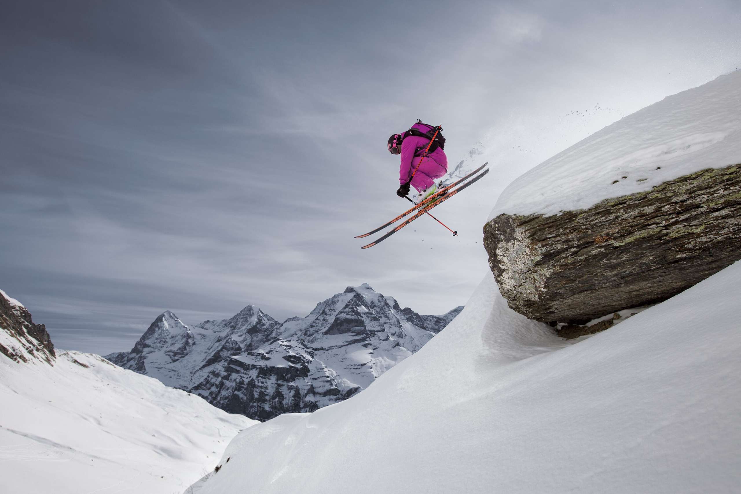 Un skieur saute par-dessus une falaise dans le domaine skiable de Mürren-Schilthorn. La triade Eiger, Mönch et Jungfrau est visible au loin.