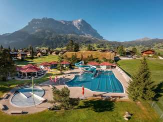 A bird's-eye view of the outdoor pool in Grindelwald, with houses and the Eiger in the background.
