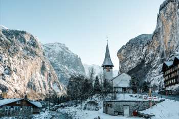 The church in the village of Lauterbrunnen in winter. The Staubbach Falls are visible in the background.