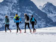 Zwei Läufer beim Winter Trail Running auf Grindelwald First, im Hintergrund der Eiger.
