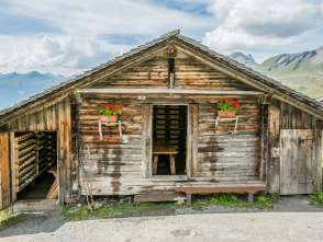 A small cabin on the Schwarzwaldalp with geraniums along the facade. The door is open.