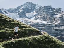 A runner on the mountain course of the Jungfrau Marathon. Scattered snowfields and glaciers on the mountain can be seen in the background.